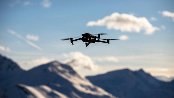 Dron volando sobre montañas: turismo de aventura