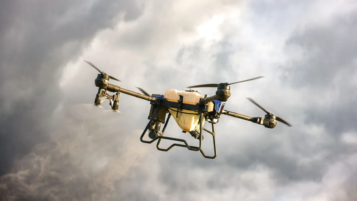 Un dron agrícola grande de ocho rotores, con su depósito, en vuelo bajo un cielo de tormenta
