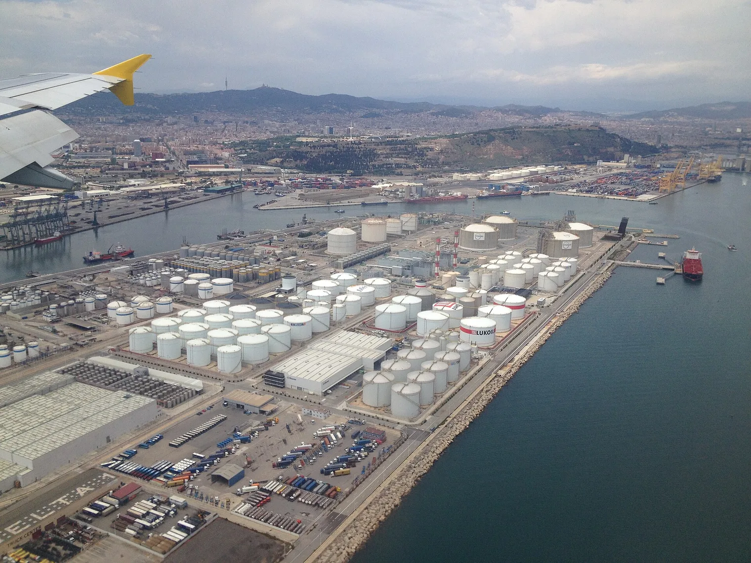 Vista aérea del puerto de Barcelona, con sus terminales de contenedores, los depósitos de graneles líquidos y la ciudad al fondo