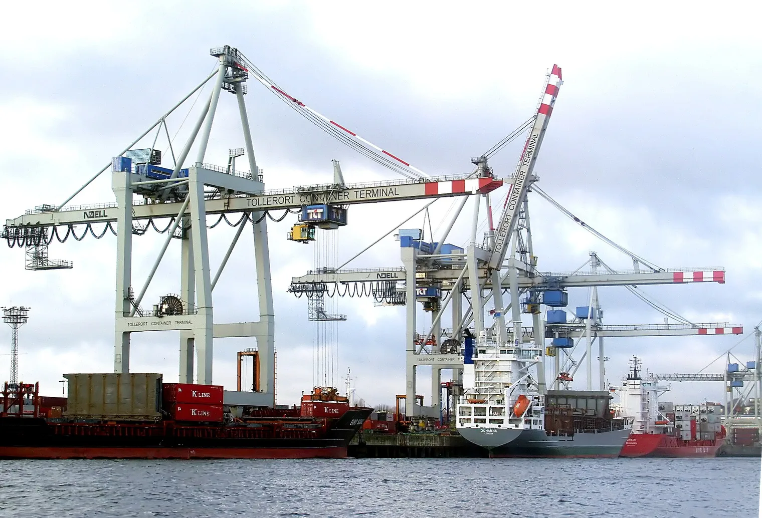 Grúas pórtico azules y naranjas en una terminal de contenedores del puerto de Hamburgo, con un buque de Hamburg Süd atracado
