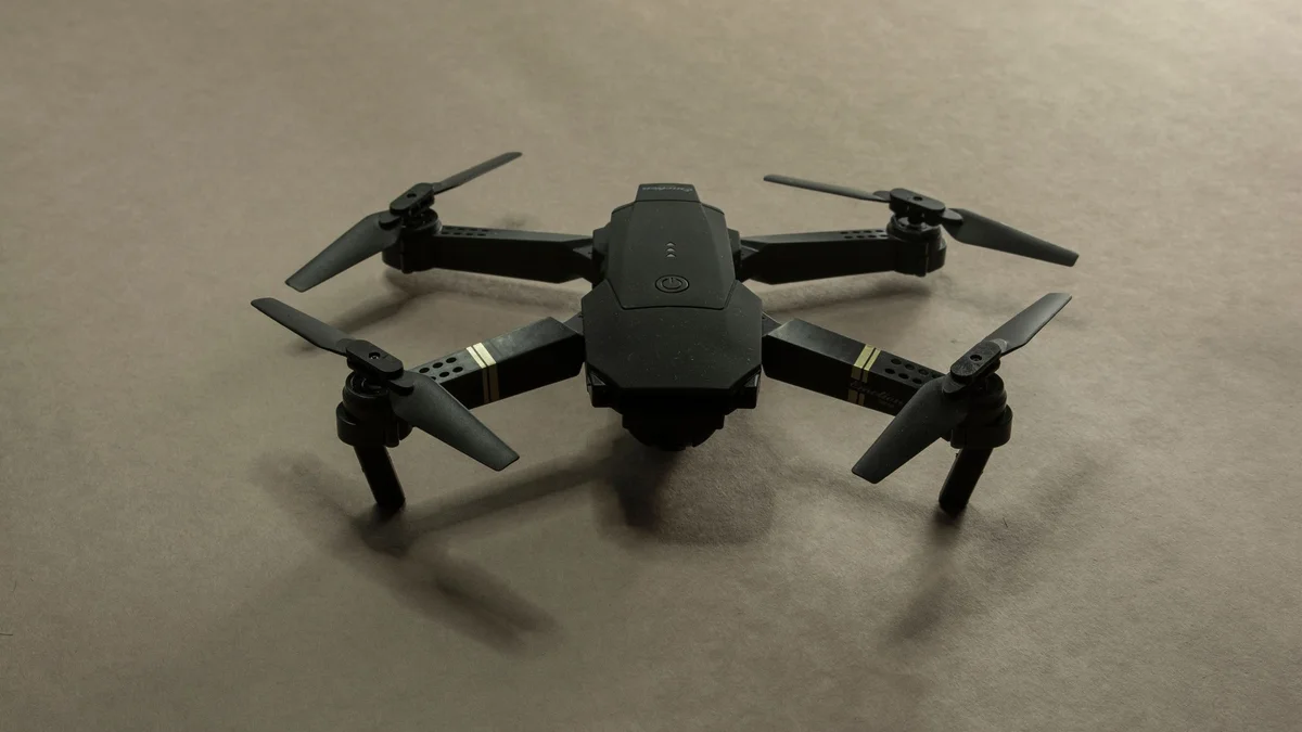 Dron plegable de juguete, negro, del tipo del E88 Pro, sobre un fondo liso
