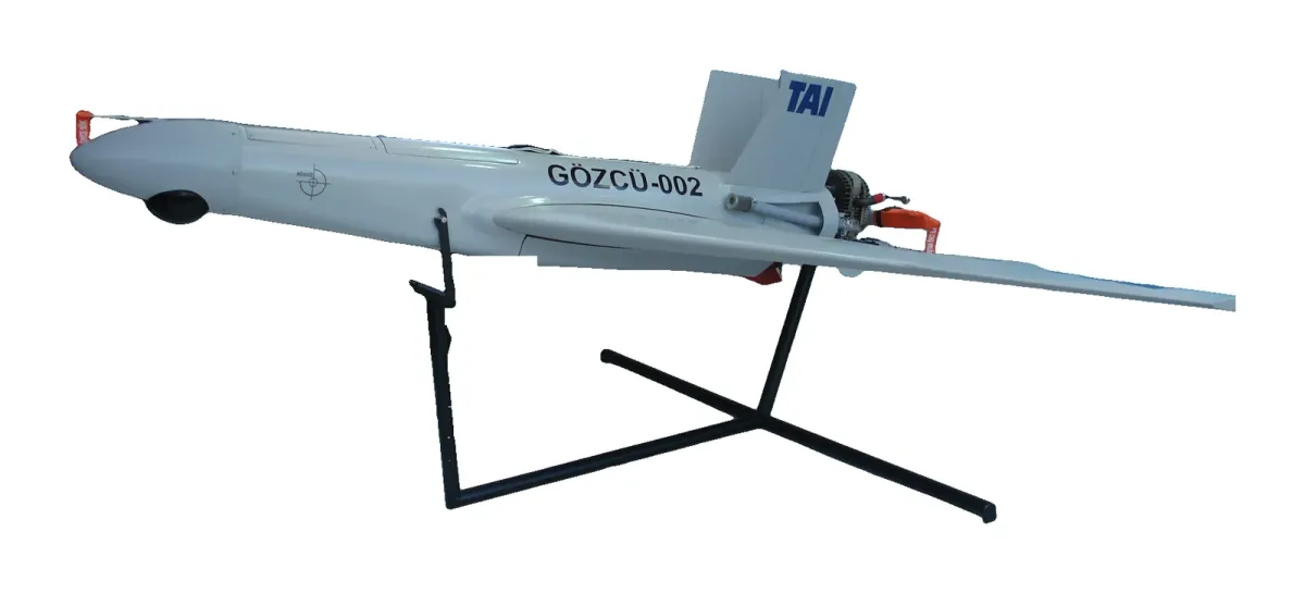 TAI Gözcü — Sobre su soporte de exposición, en IDEF 2007. Imagen: KIZILSUNGUR at Turkish Wikipedia · CC BY-SA 3.0 · Wikimedia Commons (recortada sobre fondo blanco) — https://commons.wikimedia.org/wiki/File:GozcuIHA01.JPG